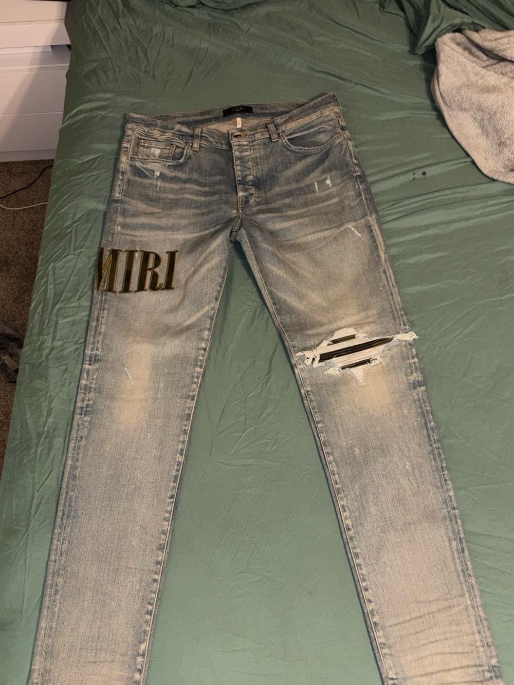 AMIRI Light Blue Distressed Skinny Jeans with Gold Logo